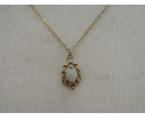 A small opal pendant in a yellow metal moulded mount on a yellow metal chain stamped 9ct