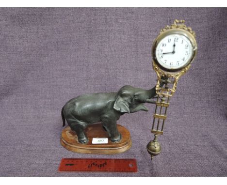 A late 19th century/early 20th century mystery clock modelled as cast elephant figure on wood base holding swinging pendulumC