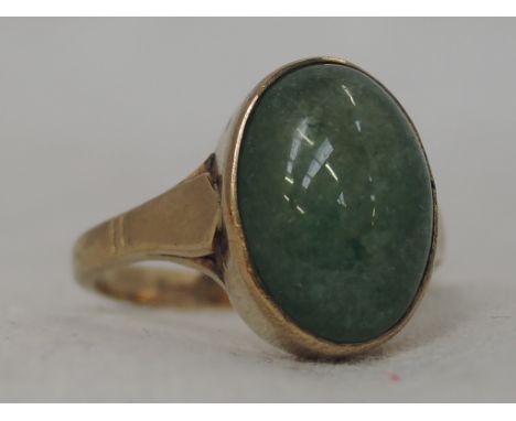 A lady's dress ring having a jade cabouchon stone in a collared mount on a yellow metal loop stamped 9ct,  size P