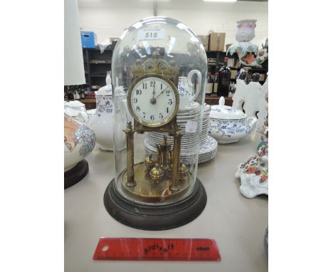 A vintage brass anniversary clock of traditional design in glass dome