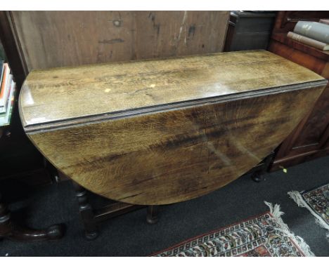 An early 20th century oak dining table having oval drop leaf top on baluster turned gate legs