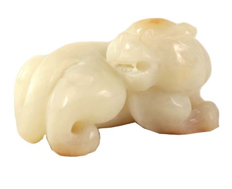 A CHINESE WHITE JADE SCULPTURE modelled as a recumbent lion with russet inclusions to the top of the head and feet5.5cm wide,