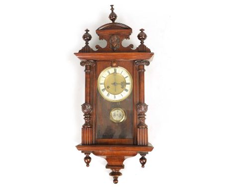 A SMALL 19TH CENTURY VIENNA STYLE WALL CLOCK with shaped masked pediment above a glazed door with turned columns and shaped b