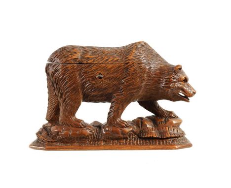 A LATE 19TH CENTURY CARVED BLACK FOREST BEAR TRINKET BOX modelled as a walking bear with inset amber glass eyes standing on n