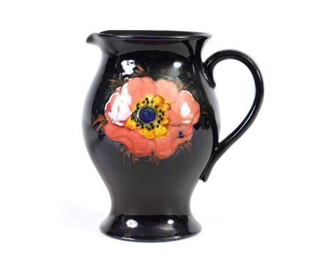 A 1930'S MOORCROFT LARGE JUG of footed baluster form tube lined and decorated with two alternate anemone flower heads on a da