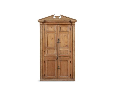 A 19TH CENTURY STRIPPED PINE CUPBOARD WITH ARCHITECTURAL PEDIMENT,above twin fielded panel doors enclosing a fitted interior 