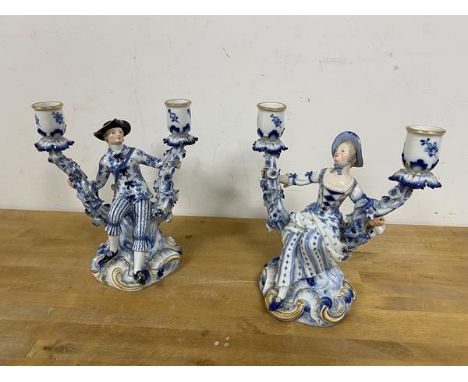 A pair of Dresden 20thc candlesticks each with a figure flanked by two candle holders both with crossed swords to base measur