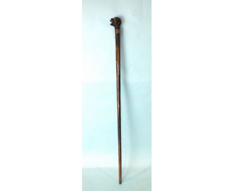 A hardwood novelty walking cane, the handle carved with a dog with an open mouth, having a push button mechanically-operated 