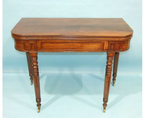 A George IV mahogany fold-over card table, having a concealed frieze drawer on ring-turned legs with castors, 97cm wide, toge