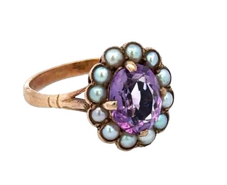 An oval amethyst and seed pearl cluster ring, stamped 9ct. Amethyst has a mid purple hue and is approx 9mm x 7mm with only mi