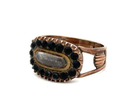Georgian mourning ring with a glazed central panel containing plaited hair, surrounded by faceted black stones on a rose meta