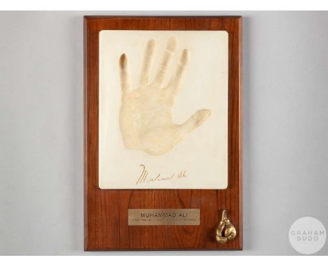 A plaster cast of Muhammad Ali's handprint, with a cast image of his signature, metal plaque fixed to base detailing the lege