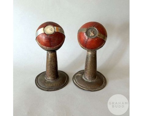 Matched pair of leather cricket balls, one with inset shilling, rubbed and the other with inset medal with wickets and crosse