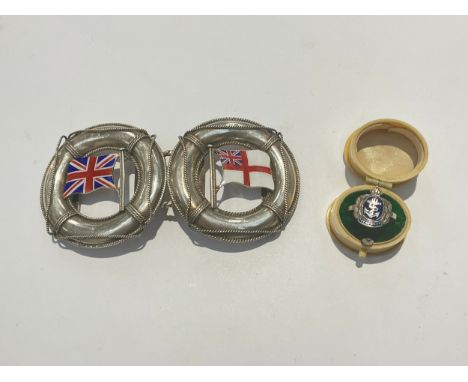 A silver belt buckle as two joining lifebelts, one with Union Flag, the other with White Ensign flag, together with a Royal N