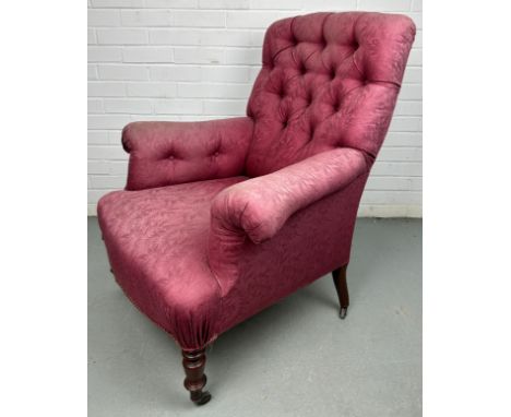 A VICTORIAN BUTTON BACK ARMCHAIR IN THE MANNER OF HOWARD AND SONS, Upholstered in raspberry coloured fern print fabric, raise