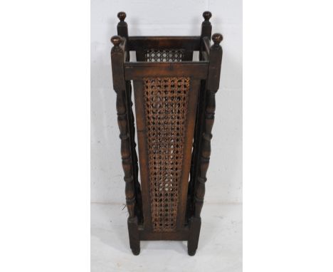 An antique oak stick stand, with bergère sides and turned detailing