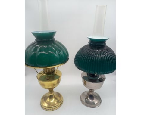 A vintage brass oil lamp with green glass shade complete with chimney along with a chrome one with similar shades.