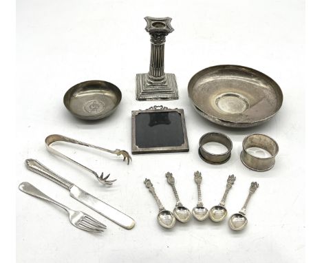 A collection of silver and white metal items including a silver candlestick, photo frame, cutlery, dishes etc.