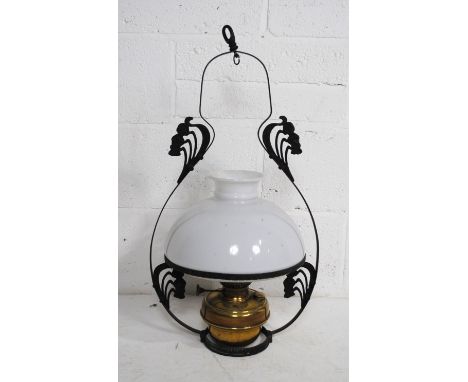 A wrought iron framed hanging oil lamp with glass shade