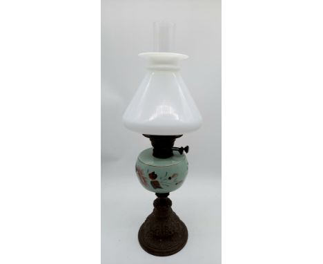 An antique oil lamp with blue opaline glass reservoir decorated with flowers, milk glass shade and chimney, on spelter base.