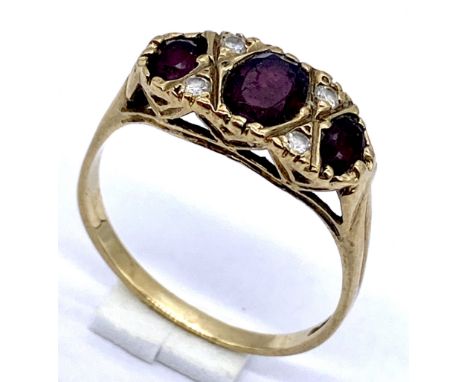 A garnet three stone ring with diamond infills set in 9ct gold, size S