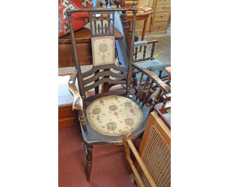 An early 20th Century stained beech framed panel back elbow chair with circular upholstered seat panel, set on turned support