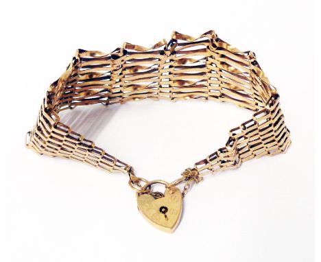 A yellow metal gate-link bracelet with hallmarked 375 gold heart shaped padlock and safety chain