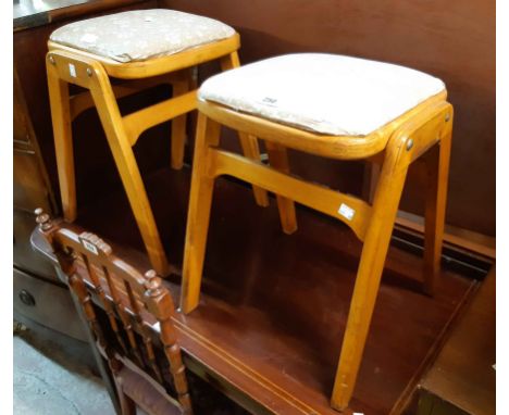 A pair of vintage stained wood kitchen stools with later upholstered seats, set on splayed legs