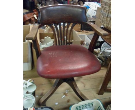 A vintage stained wood framed curved back swivel office elbow chair with studded red leatherette upholstery, set on a Stone's