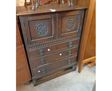 A 78cm 20th Century stained oak cabinet in the antique style with pair of carved panel doors and three long graduated drawers