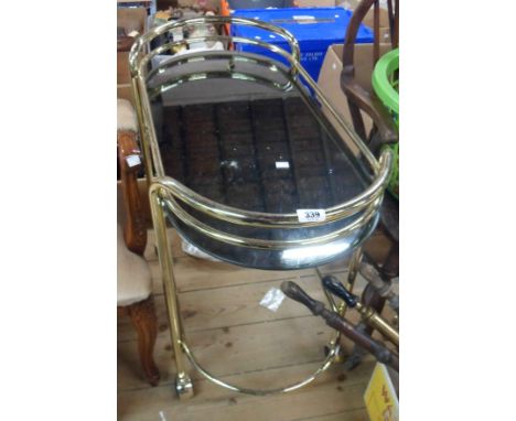 A vintage brassed metal framed and smoked glass oval cocktail table, set on casters - some tarnish