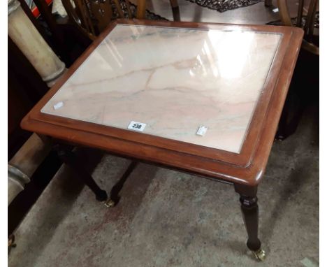 A 61cm modern stained wood and pink marble topped tea table, set on turned and faceted legs with brass roller casters