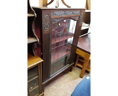 A 91cm early 20th Century walnut display cabinet with decorative carved relief cartouches and material lined interior enclose