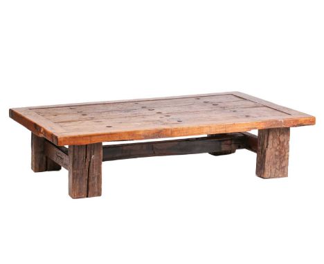 A large coffee table, constructed from a vintage door with metal studs, on bold square section timber legs, 181 x 119 cm, 44 