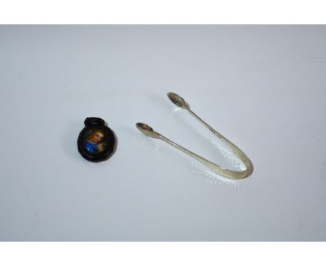 A Victorian jet pendant with painted panel showing a girl with her pet rabbit, together with a pair of silver sugar tongs wit