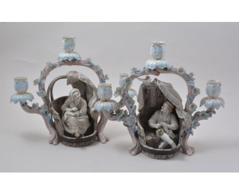 Pair of French porcelain three light novelty candelabra, modelled with Cobbler, a Woman Darning, encrusted with flowers, 27cm