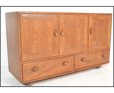 A mid century beech and elm Ercol Windsor pattern sideboard dresser. Raised on ball castors having end cupboards with a bank 