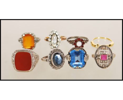 A collection of silver rings to include an art deco style having geometric pierced decoration set with a square cut pink ston