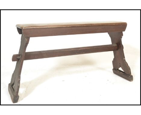 A early 20th Century stained pine bench raised on shaped supports united by a&nbsp;pegged stretcher&nbsp;below a single&nbsp;