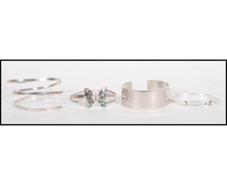 A group of four stamped 925 silver bangle bracelets to include a butterfly bangle set with mother of pearl, a wide bangle of 