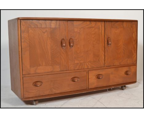 A stunning mid 20th Century Ercol beech and elm Windsor pattern sideboard credenza, three cupboard doors over two long drawer