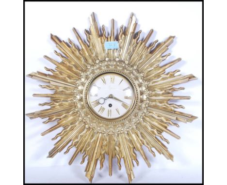 A vintage 20th Century Art Deco style sunburst starburst rising sun wall clock having a gilt decorated wooden frame. Central 