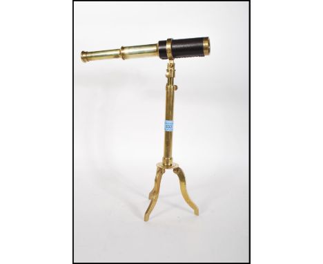 A vintage 20th Century brass table / desk top telescope being leather bound and raised on a brass metamorphic tripod base.&nb