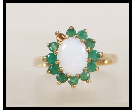 A hallmarked 9ct gold ring set with a central opal cabochon with a halo of green stones. Hallmarked Birmingham 1979. Weight 2