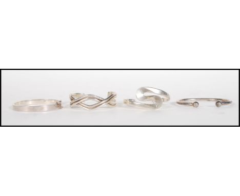 A group of four stamped 925 silver bangle bracelet to include a cross over design bangle, a curved design bangle, an open ban