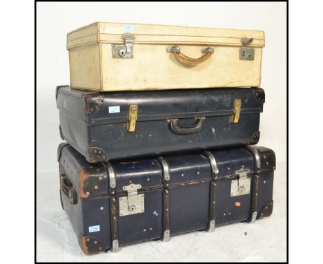 A stack of mid century vintage suitcases to include a black faux leather example with another faux cream leather case and a c