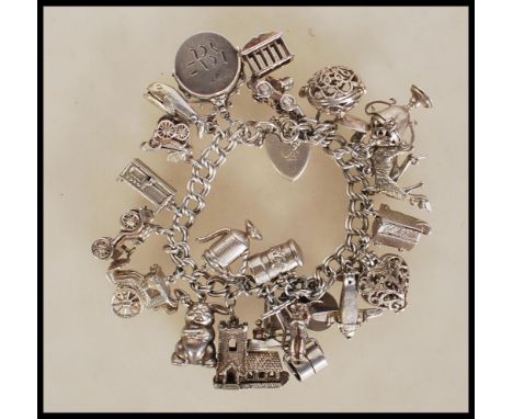 A silver hallmarked charm bracelet having heart padlock clasp with an assortment of silver charms to include plane, house, ch