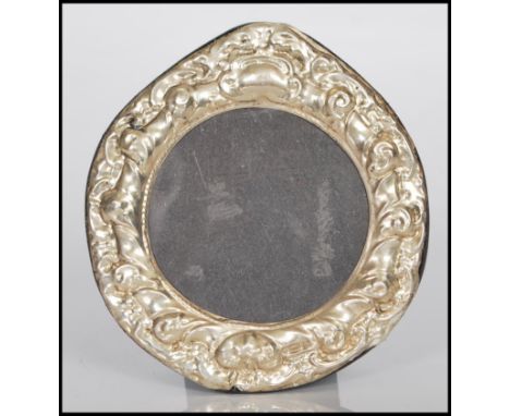 A sterling silver easel back photograph picture frame of circular form having rococo style relief decoration.