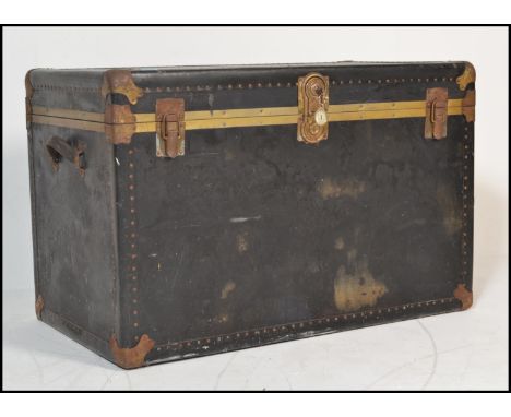 A large vintage travel trunk chest having metal brass style banding with leather carrying handles to both sides and locks / c
