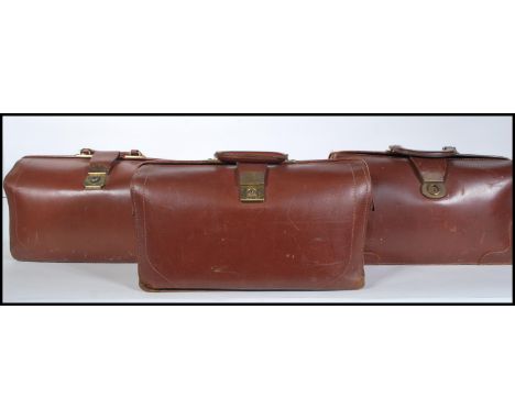 A collection of three vintage early to mid 20th Century Gladstone leather bags. Each having brass latches / locks to the top 